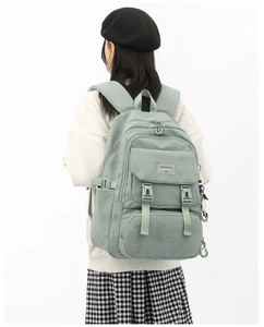 Detail of light green backpack showing multiple compartments and adjustable straps for school