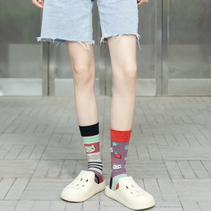 Close-up of mismatched crew socks featuring colorful stripes, cat patterns, and strawberries