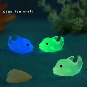 Luminous resin dolphin figurines in blue and green on a decorative deep sea sand base