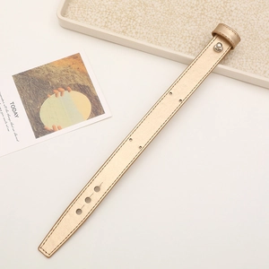Detail of a golden leather wrist strap with metallic finish and adjustable buckle holes