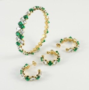Künstlerische Anordnung von Goldschmuckset mit grünen und weißen quadratischen Edelsteinen