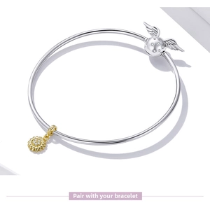Detail of silver bangle bracelet featuring golden sunflower and golden snitch charms