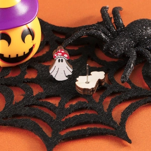 Macro shot of Halloween ghost earrings with mushroom hats and metal studs on a spider web