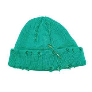 Détail du bonnet en maille vert émeraude effet usé avec épingle de sûreté et anneaux