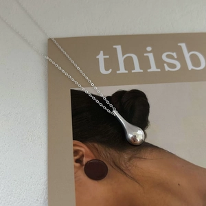Minimalist 925 sterling silver water drop pendant necklace on a fashion magazine