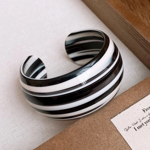 Detailed top view of a wide resin open bangle featuring bold black and white stripes