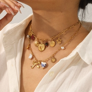 Detail of layered gold necklace with moon, sun, and heart charms on a model