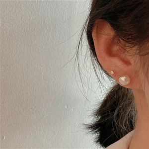 Detail of s925 gold stud and irregular baroque pearl earring on model ear lobe