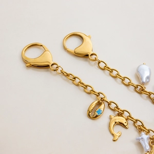 Close-up of gold-plated marine ocean charms with shell, dolphin and pearl details