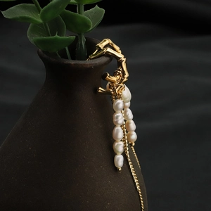 Natural pearl earrings with bamboo design and gold tassel hanging on a ceramic vase