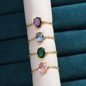 Detail view of four gold-plated chain rings with colorful oval-cut cubic zirconia stones