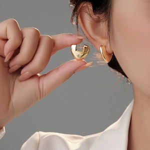 Macro view of gold heart earrings showing the polished geometric metallic design