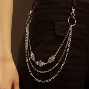 Detail of silver multi-layered waist chain with Hamsa and eye charms on black trousers