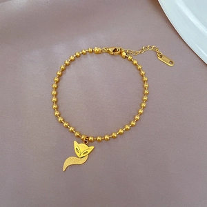 Detail of a golden stainless steel bead bracelet featuring a polished fox pendant on lavender
