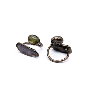 Detail of vintage bronze rings with green oval and dark grey raw natural stones