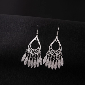 Detailed close-up of bohemian silver leaf fringe earrings on black leather texture