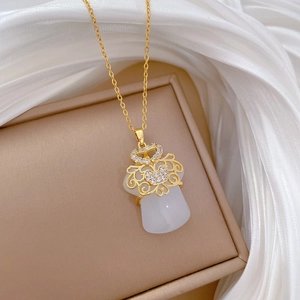 Detail of gold titanium necklace featuring a white jade pendant with sparkling zircons
