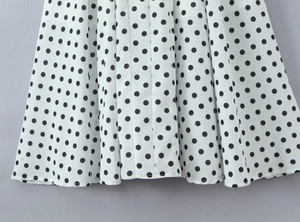 Détail rapproché d'un tissu blanc à pois noirs avec une texture légère