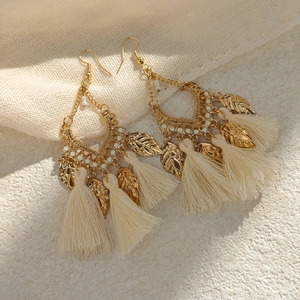 Detail of Bohemian tassel earrings with golden leaf charms and off-white bead accents