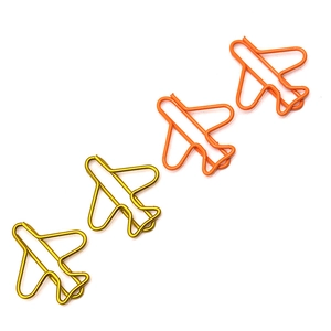 Close-up of airplane shaped paperclips in gold and orange metal on white background