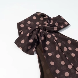 Detailansicht des braunen Oberteils mit rosa Punkten und zarter Chiffon-Schleife