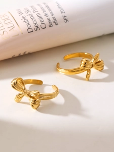 Close-up of golden ribbon bow rings with polished metallic finish on a soft background