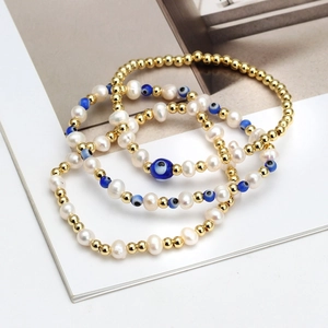 Three-piece stackable bracelet set with gold beads, pearls, and blue evil eye charms