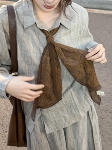 Détail d'un mannequin portant un collier foulard en soie marron à motif cachemire