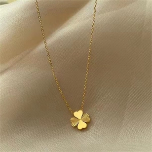 Macro shot of 18k gold four-leaf clover pendant with heart-shaped leaves on beige silk