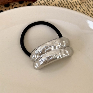 Detail of silver wavy metal ornament on thick black elastic hair tie with modern style
