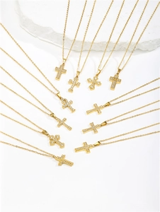Detailed view of multiple gold-plated cross pendants with cubic zirconia on white stone