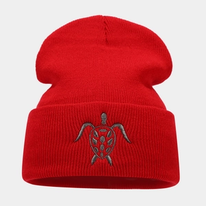 Detailed close-up of a red ribbed beanie featuring grey sea turtle embroidery texture