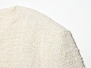 Macro-opname van gebreide gebroken witte stof met textuurpatroon voor damesjasje