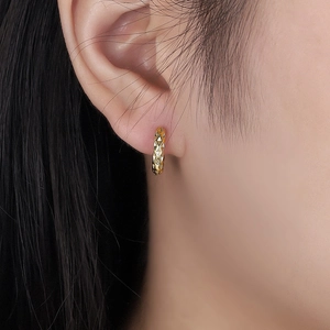 Star and moon themed gold hoop earrings with geometric diamond texture on model