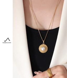 Detail of French vintage gold hat pendant necklace with pearl inlay on a female model