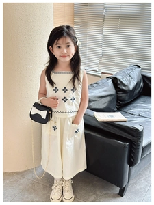 Close-up of floral embroidery and scalloped trim on cream cotton linen children's outfit