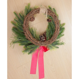 Detail of Christmas wreath with natural pine cones, PE leaves and red satin ribbon bow