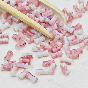 Détail macro de perles en céramique cylindriques avec veinures de marbre rouge