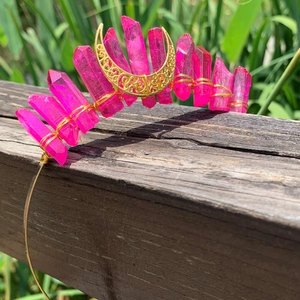 Handmade pink crystal crown headband with gold wire wrap and moon decor on wood fence