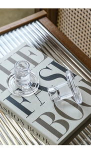 Detail of two clear T-shaped glass candle holders set on a book for home decor