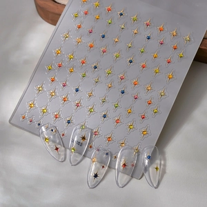 3D nail art stickers with gold star patterns and colorful gemstones shown on clear tips