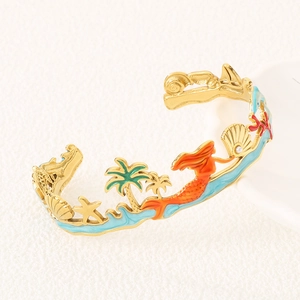 Detail of gold open bracelet featuring enamel mermaid, palm tree and starfish charms