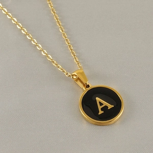 Vue macro d'un collier en or 18 carats avec pendentif lettre A en émail noir chic