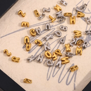 Détail macro de pendentifs lettres creuses en or 18 carats et argent pour bijoux DIY