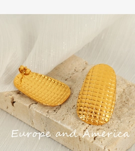 Macro view of gold plated spiral earrings with a fine mesh texture on a stone base
