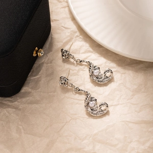 Gros plan de boucles d'oreilles argentées avec perles et motif rose sur papier texturé