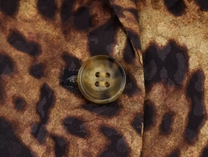Detalle de tela con estampado de leopardo y botón de resina ámbar en un blazer de moda