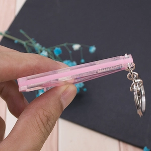 Pink hollow acrylic alphabet keychain with gold ring shown from a side view for thickness
