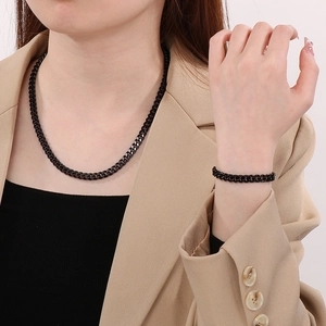 Close-up of black stainless steel Cuban link necklace and bracelet set on a model