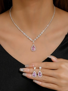 Detail view of pear-cut pink zircon necklace and earrings set on a model with black clothing